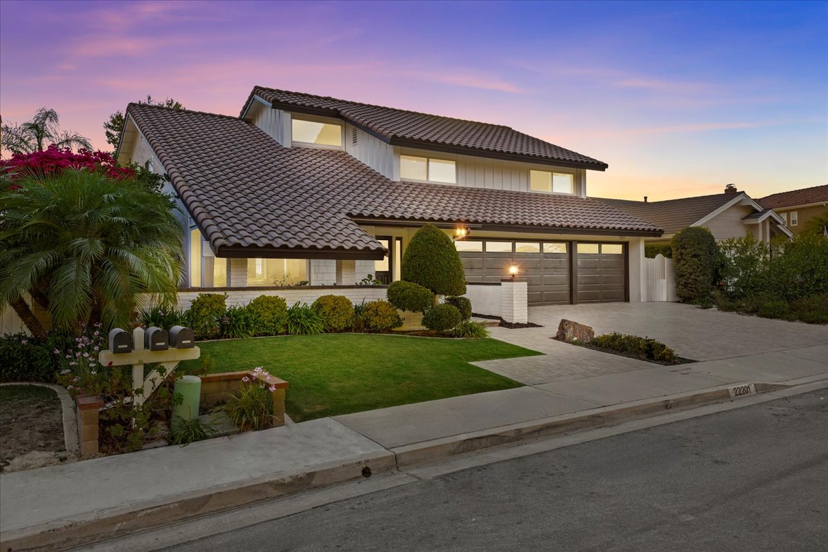 Single-level ranch-style home with tile roof and three-car garage at sunset in Mission Viejo
