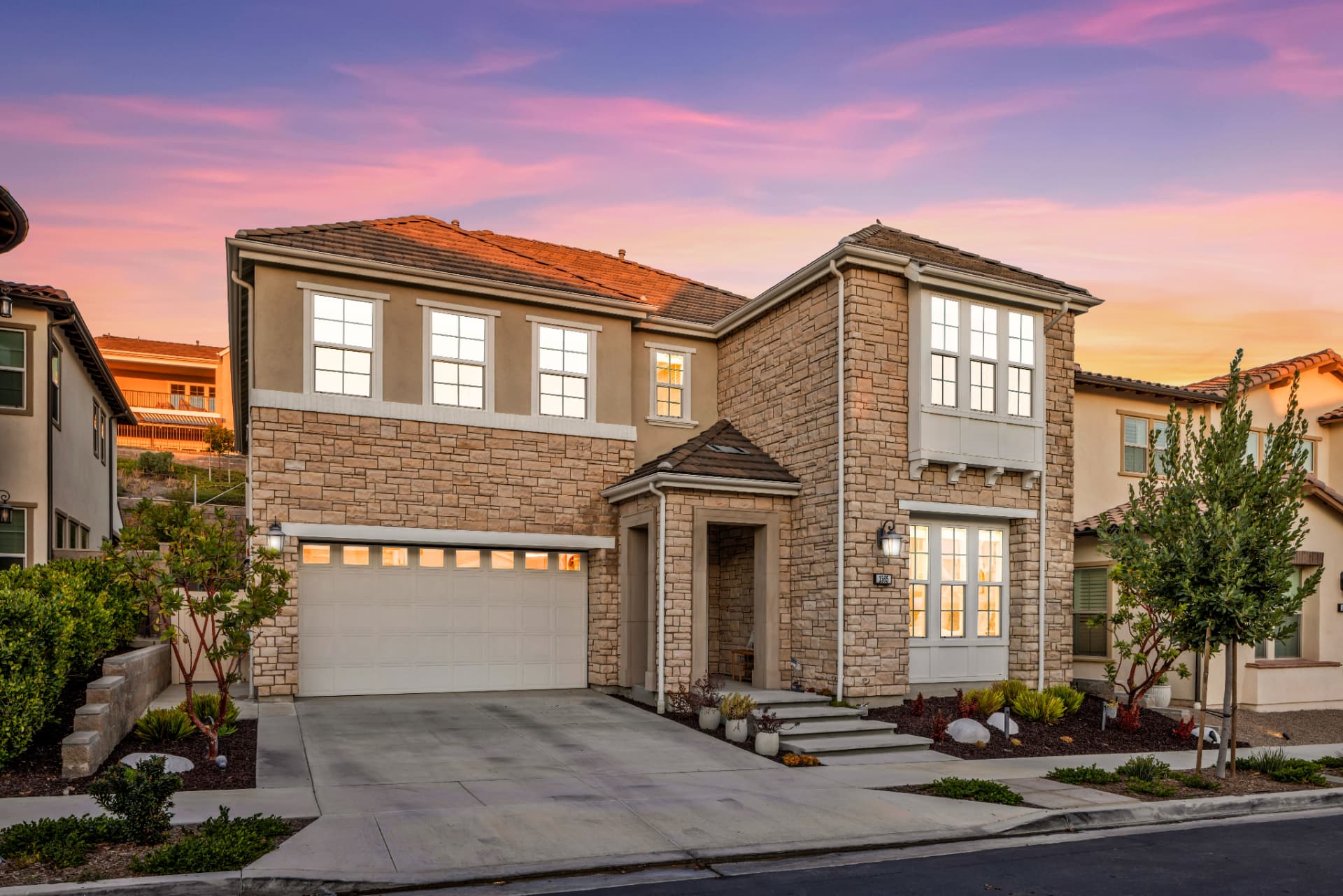 Two-story home with stone facade and lit windows at dusk in Lake Forest